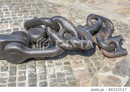 Massive black anchor chain on paving stones Massive black anchor chain on paving stones 80332537