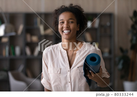 Head shot portrait excited African American woman holding yoga mat 80333244