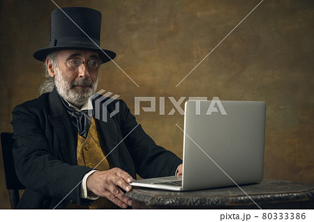 Half-length retro portrait of sad elderly gray-haired man, gentleman, aristocrat or actor isolated on dark vintage background. Retro style, comparison of eras concept. Half-length retro portrait of sad elderly gray-haired man, gentleman, aristocrat or actor isolated on dark vintage background. Retro style, comparison of eras concept. 80333386