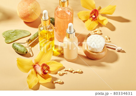 Cosmetic care products in glass bottles with orchid flowers - serums, cream, gel, oils. Concept for face and body care, wellness and spa, tropical relaxation. 80334631