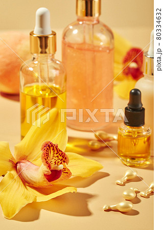 Cosmetic care products in glass bottles with orchid flowers - serums, cream, gel, oils. Concept for face and body care, wellness and spa, tropical relaxation. 80334632