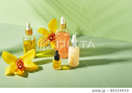 Cosmetic care products in glass bottles with orchid flowers - serums, cream, gel, oils. Concept for face and body care, wellness and spa, tropical relaxation. 80334659