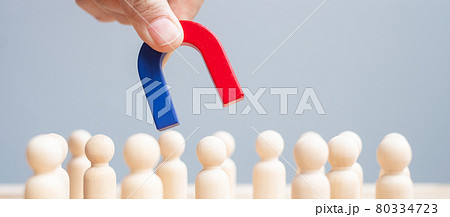 Business man hand holding magnet and pulling man wooden figure from the crowd employee. Business, Human resource management, Recruitment, Teamwork, strategy, toxic people and leadership Concepts 80334723