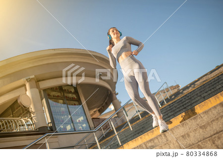 Fit girl in grey sportswear having cardio warm up on the stairs 80334868