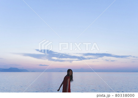 夕暮れの海にいる赤いワンピースの女性 80338000
