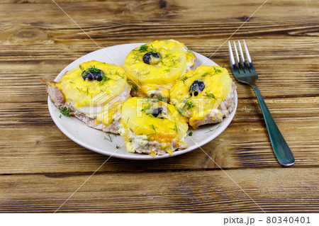 Pieces of baked pork with pineapple, cheese and olive on a wooden table 80340401