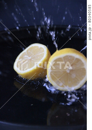 Lemons splashing into water on dark background 80340585