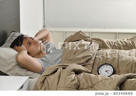 Depressed young Asian man lying in bed cannot sleep from insomnia Depressed young Asian man lying in bed cannot sleep from insomnia 80340689