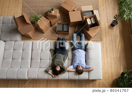 Young married couple rest on cozy couch after packing stuff 80341767