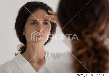 Young latin woman look at mirror see acne on face Young latin woman look at mirror see acne on face 80344210