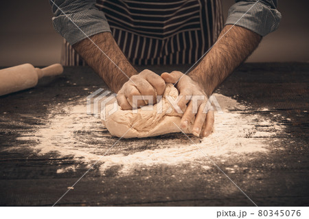 Male hands knead the dough. 80345076