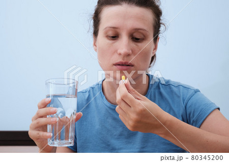 A woman takes a capsule of medicine. Consumption of the drug. Treatment of the disease 80345200