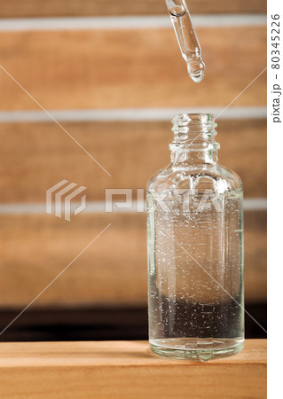 Serum with pipette in cosmetic bottle on wooden podium. Skincare, health care concept. Top view. 80345226