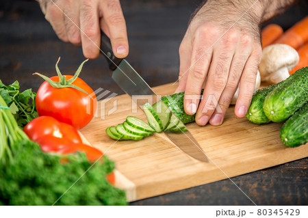 Male hands cutting vegetables for salad Male hands cutting vegetables for salad 80345429