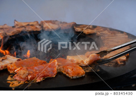 Chef with tongs grilling meat steaks on brazier - close up Chef with tongs grilling meat steaks on brazier - close up 80345430