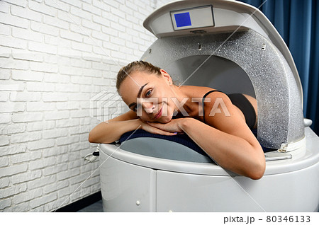 Happy cute woman smiling at camera lying in spa capsule enjoying professional beauty treatment in spa salon Happy cute woman smiling at camera lying in spa capsule enjoying professional beauty treatment in spa salon 80346133
