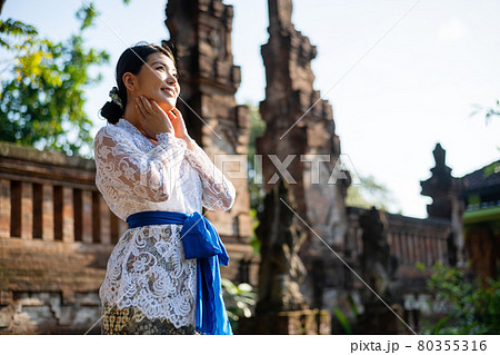 バリ島の伝統寺院にいる伝統衣装(クバヤ)を着た女性 80355316