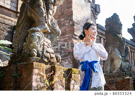 バリ島の伝統寺院にいる伝統衣装(クバヤ)を着た女性 80355324