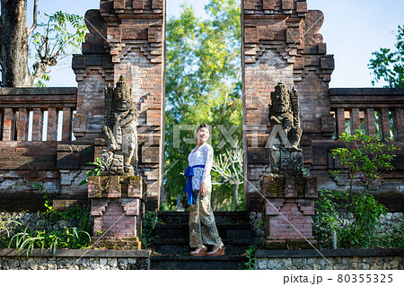 バリ島の伝統寺院にいる伝統衣装(クバヤ)を着た女性 80355325