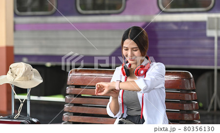 Happy young woman traveler waiting for train at the train station. Happy young woman traveler waiting for train at the train station. 80356130