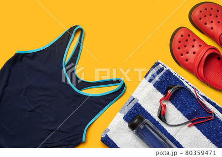 Flat lay summer pool accessories on a yellow background. Colorful beach wear. 80359471