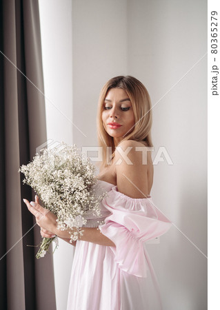 Pretty smiling young woman standing with a bouquet Pretty smiling young woman standing with a bouquet 80365279