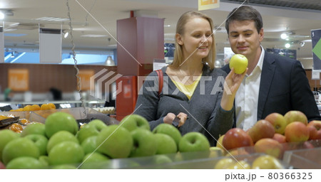 Happy young couple buying apples in the supermarket 80366325