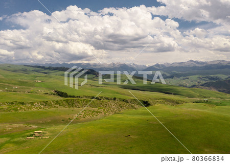 Mountain peaks and grassland are under white clouds. Mountain peaks and grassland are under white clouds. 80366834