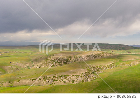Mountain peaks and grassland are under white clouds. Mountain peaks and grassland are under white clouds. 80366835