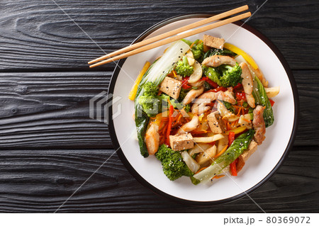 Stir fried of chicken, tofu, bell peppers, carrots, broccoli and bok choy close-up in a plate. horizontal top view 80369072