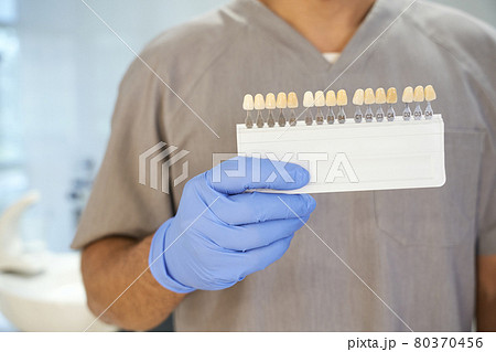 Dentist posing with teeth-whitening kit in his office Dentist posing with teeth-whitening kit in his office 80370456
