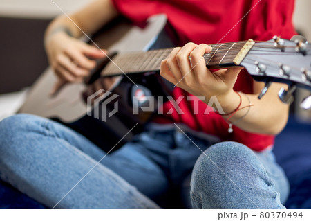 Close up shot of hand of young woman in casual clothes playing guitar Close up shot of hand of young woman in casual clothes playing guitar 80370494