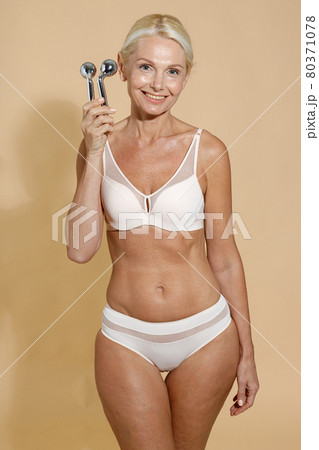 Premium Photo  Natural mature blonde woman in underwear with fit body and  glowing skin holding metal lift anti