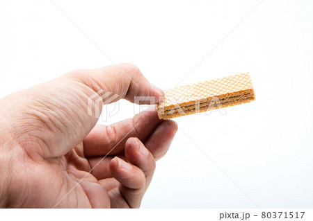 Hand holding a delicious wafer. Hand holding a delicious wafer. 80371517