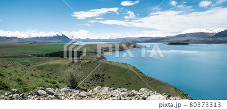 Vista with beautiful alpine scenery, turquoise glacier lake with snowy mountains in backdrop. Shot at Lake Tekapo, New Zealand Vista with beautiful alpine scenery, turquoise glacier lake with snowy mountains in backdrop. Shot at Lake Tekapo, New Zealand 80373313
