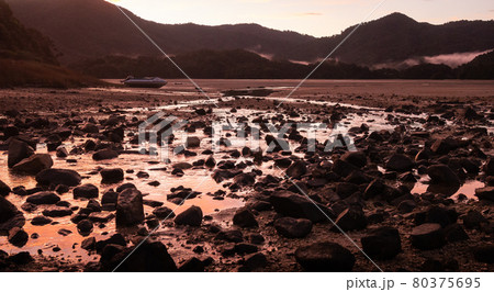 Crimson sunset in tropical inlet bay with deserted boat in frame. Landscape shot made in Abel Tasman National Park, New Zealand Crimson sunset in tropical inlet bay with deserted boat in frame. Landscape shot made in Abel Tasman National Park, New Zealand 80375695