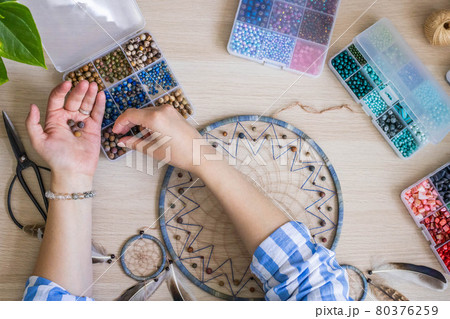 Artistic female hands use colorful beads for creating native tribal Indian amulet dreamcatcher 80376259