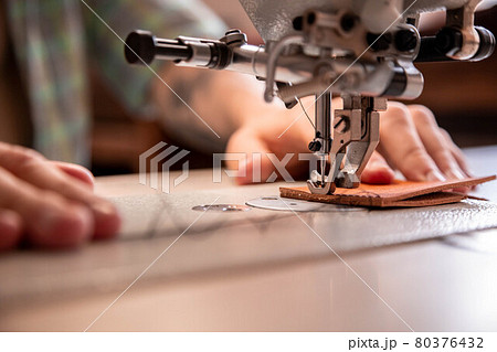 Close up craftsman hands sew stuff blank for wallet use sewing machine. Working at leather workshop 80376432