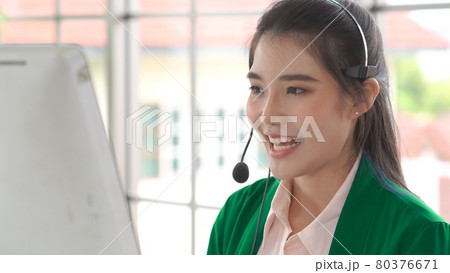 Businesswoman wearing headset working actively in office 80376671
