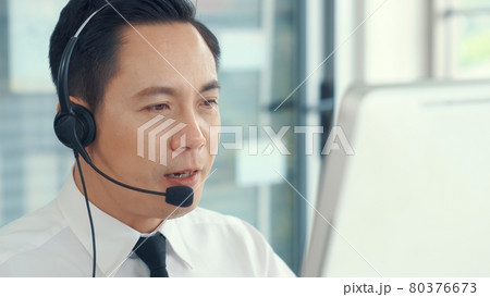 Businessman wearing headset working actively in office 80376673