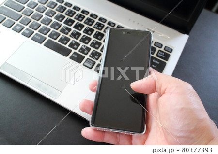 手に持つスマホとノートパソコン 手に持つスマホとノートパソコン 80377393