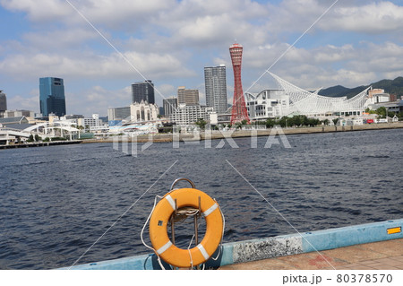 海岸のオレンジの浮き輪とその向こうに広がる海とポートタワーあるメリケンパークとビル街の見える風景 海岸のオレンジの浮き輪とその向こうに広がる海とポートタワーあるメリケンパークとビル街の見える風景 80378570