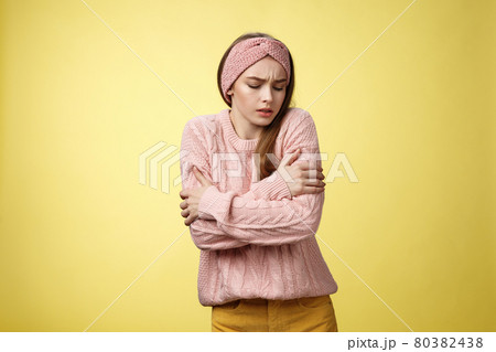 Brr girl freezing, turn-on heater. Portrait of timid cute woman wearing knitted sweater trembling from cold, embracing herself on arms looking down, stooping from discomfort cool temprature Brr girl freezing, turn-on heater. Portrait of timid cute woman wearing knitted sweater trembling from cold, embracing herself on arms looking down, stooping from discomfort cool temprature 80382438
