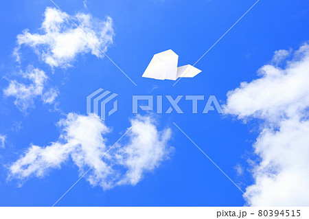 大空を飛ぶ紙飛行機の写真素材