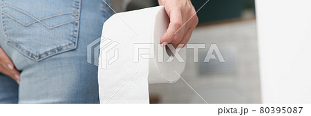 Man stands in front of toilet and holds toilet paper 80395087