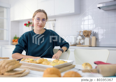 Making cakes and cookies is a lot of fun. In her kitchen, a young woman holds delicious fresh bread. Making cakes and cookies is a lot of fun. In her kitchen, a young woman holds delicious fresh bread. 80395367