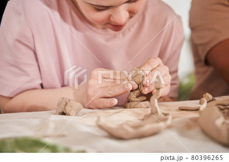 Woman with special needs working with clay in ceramic studio during the pottery workshop 80396265