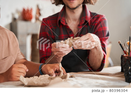 Craftsman in apron teaching young people with special needs to make a plates 80396304
