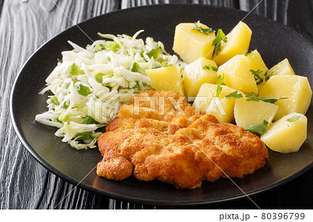 Kotlet Schabowy Polish Breaded Pork with boiled potatoes and cabbage salad close-up in a plate. Horizontal 80396799