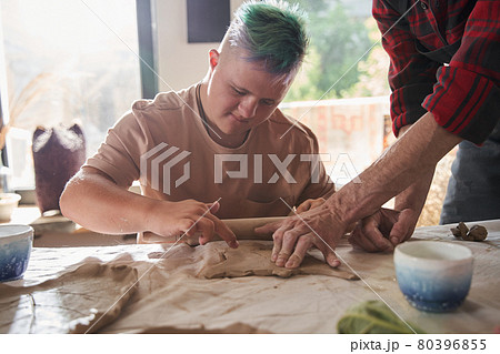 Boy with colored hair making plate from the clay at the table Boy with colored hair making plate from the clay at the table 80396855